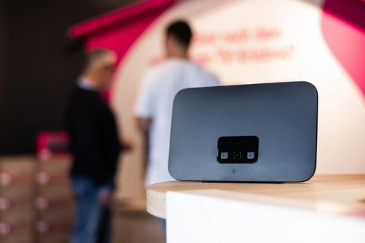 WLAN-Router auf Tisch im Telekom Shop, Kunden im Hintergrund unscharf